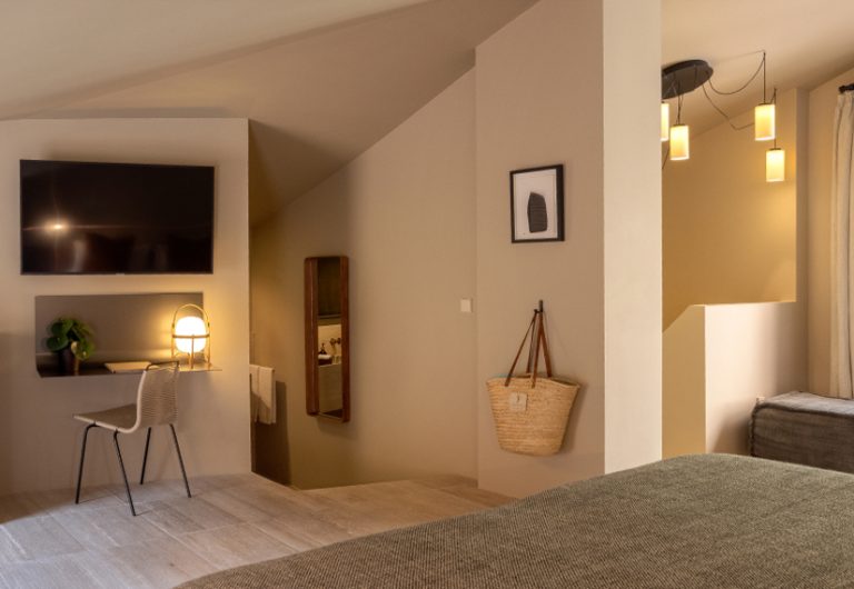 The loft room at Can Aulí: vaulted ceiling, warm amber pendants, basketwork tote