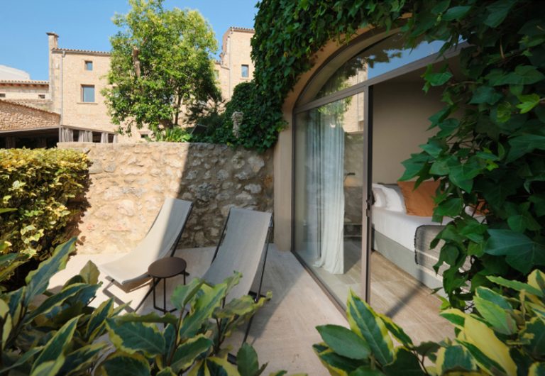 A private garden terrace with sun loungers and vines, old stone walls, the room visible behind, the Deluxe Terrace at Can Aulí